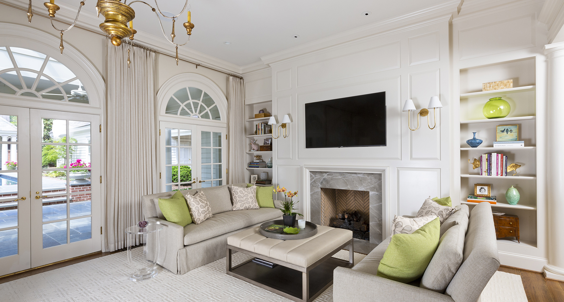 Custom all neutral living space with green couch pillows and a fireplace