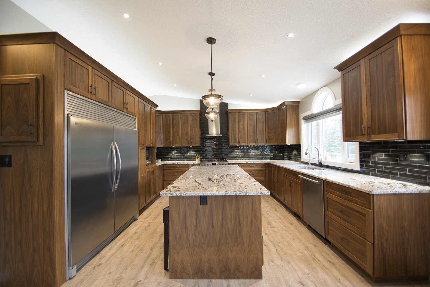 custom kitchen with natural wood finishing on cabinets and island with black tile backsplash