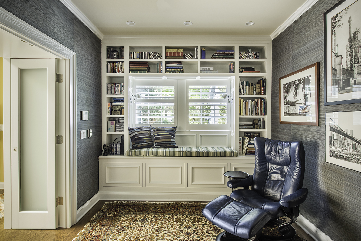 Custom reading nook with built in shelves around large window with seat inset