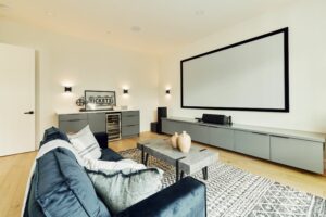 living room space with a massive projector screen, blue couch and area rug