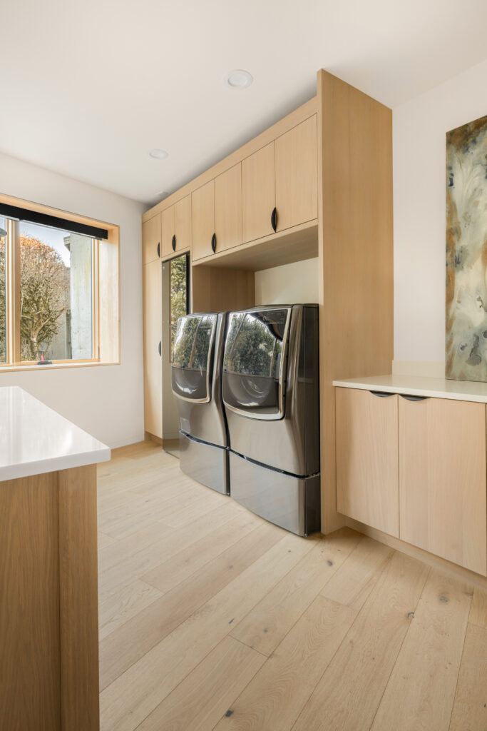 beautiful laundry room with white oak custom cabinets, a large window and an island | Alair Homes Kirkland 