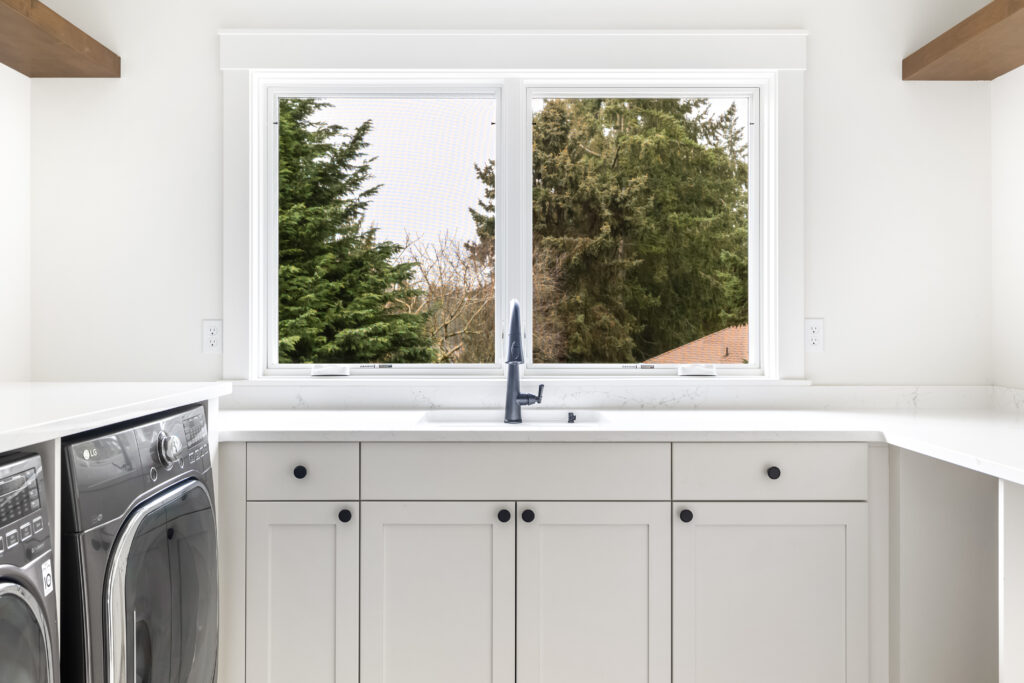 having a window is a great laundry room design idea, also large countertop, utility sink and floating shelves for storage | Alair Homes Kirkland 