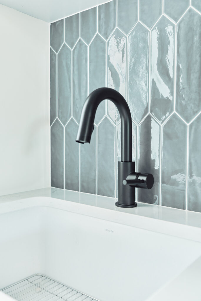 a close-up of a white sink with a black faucet i na laundry room with a vertical elongated hexagon tile, also known as a picket tile | Alair Homes Kirkland