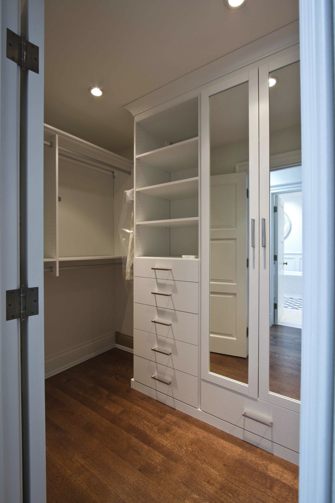 custom closet with mirrored wardrobe and built in white shelving and drawers