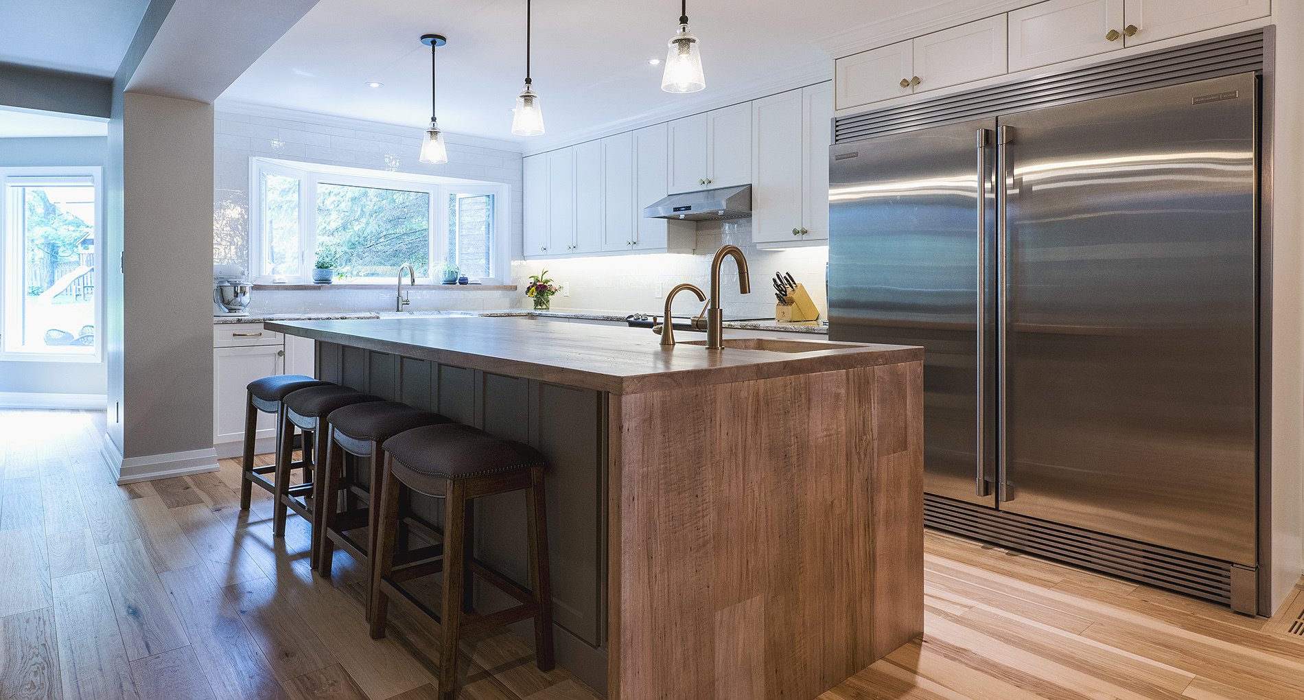 custom kitchen with large stainless steel fridge and large island with wood finishing