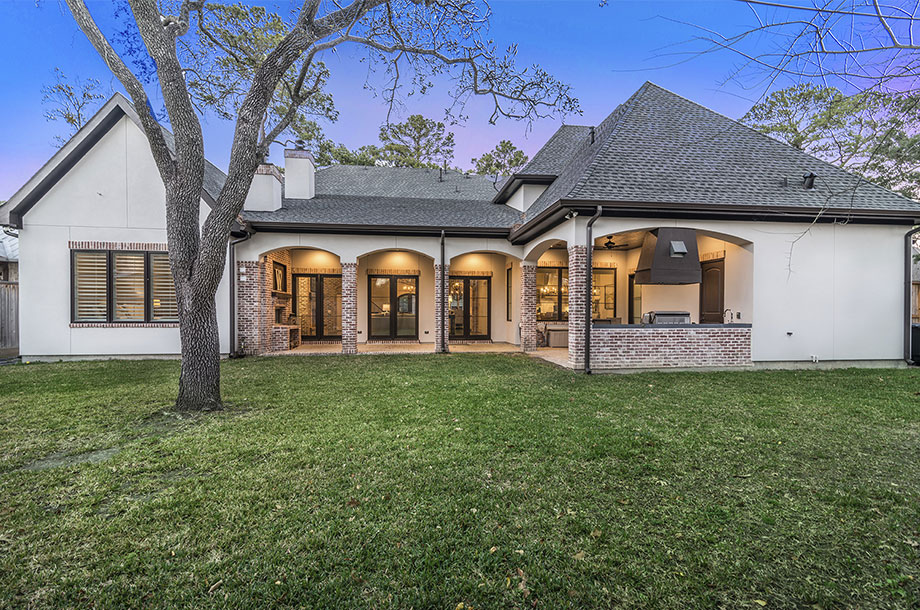 exterior of single story home with large tree planted amidst even lawn of turfgrass 