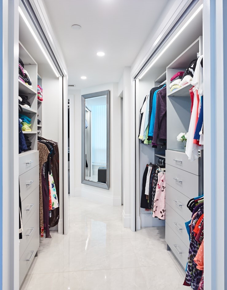 walk in closet built in shelves leading to master bath