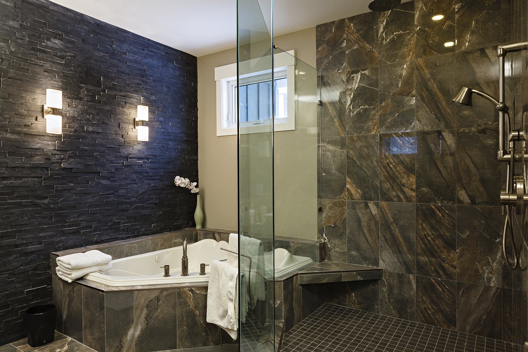 bathroom with mixed brown stone tile textured stone black wall and jacuzzi tub