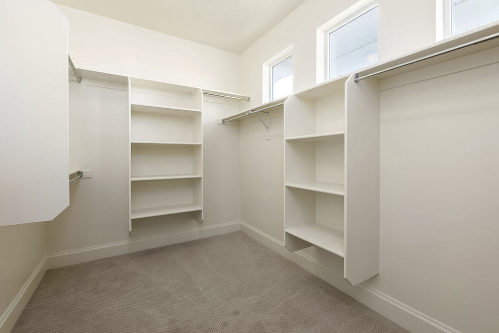 walk in closet with built in shelving and small windows 