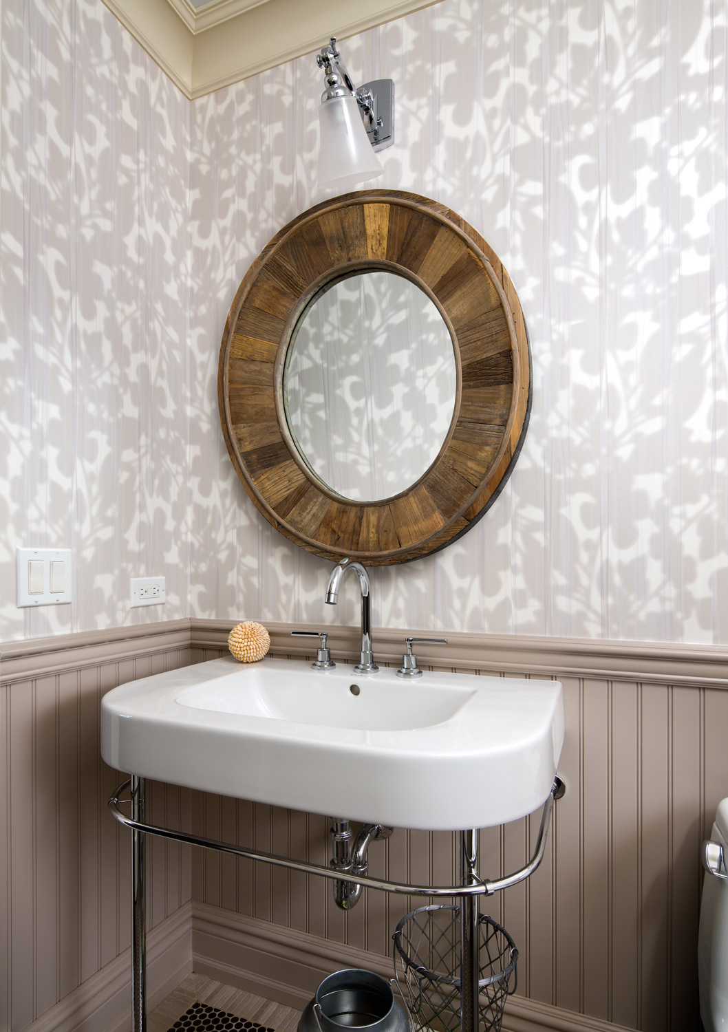 bathroom with subtly textured grey and white wallpaper and circular mirror with wood detailing