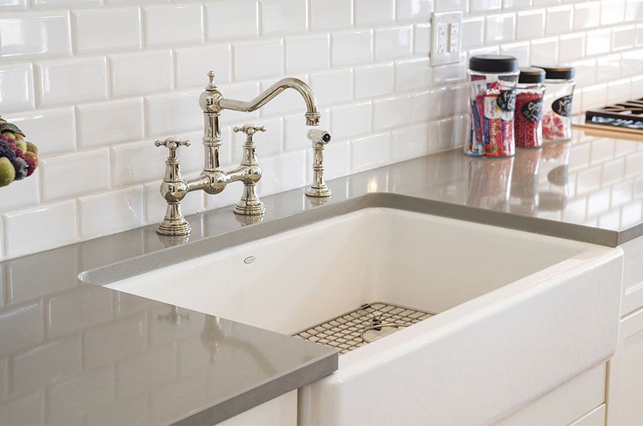 kitchen sink with rectangular white tiled backsplash and gold faucet