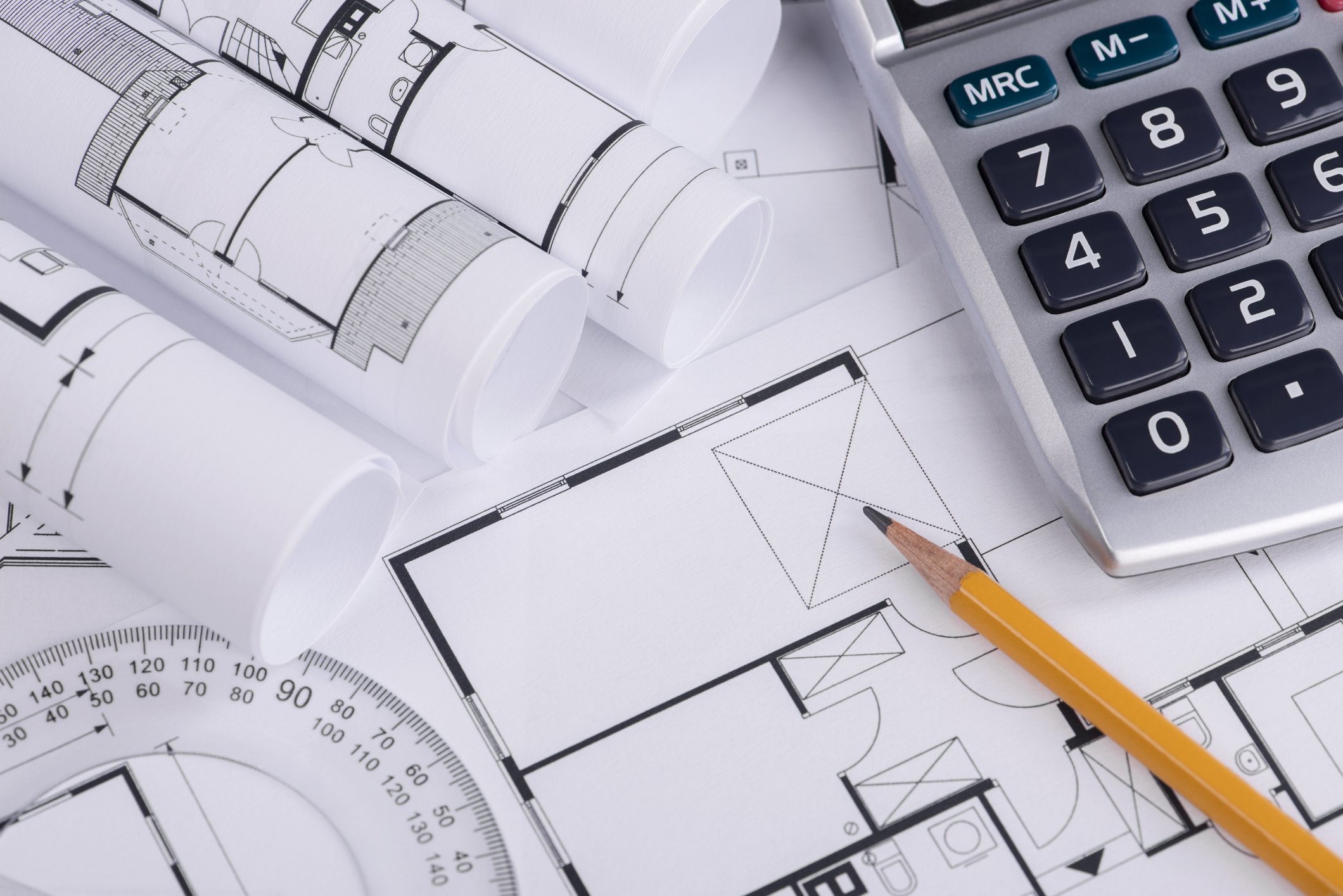 Home construction blueprints with calculator and pencil on top