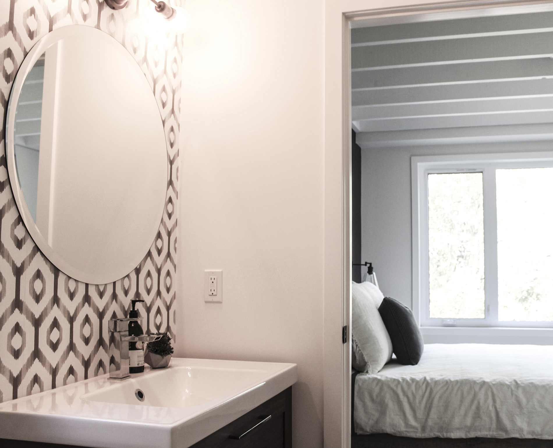 bathroom connected to guest room with patterned grey wallpaper