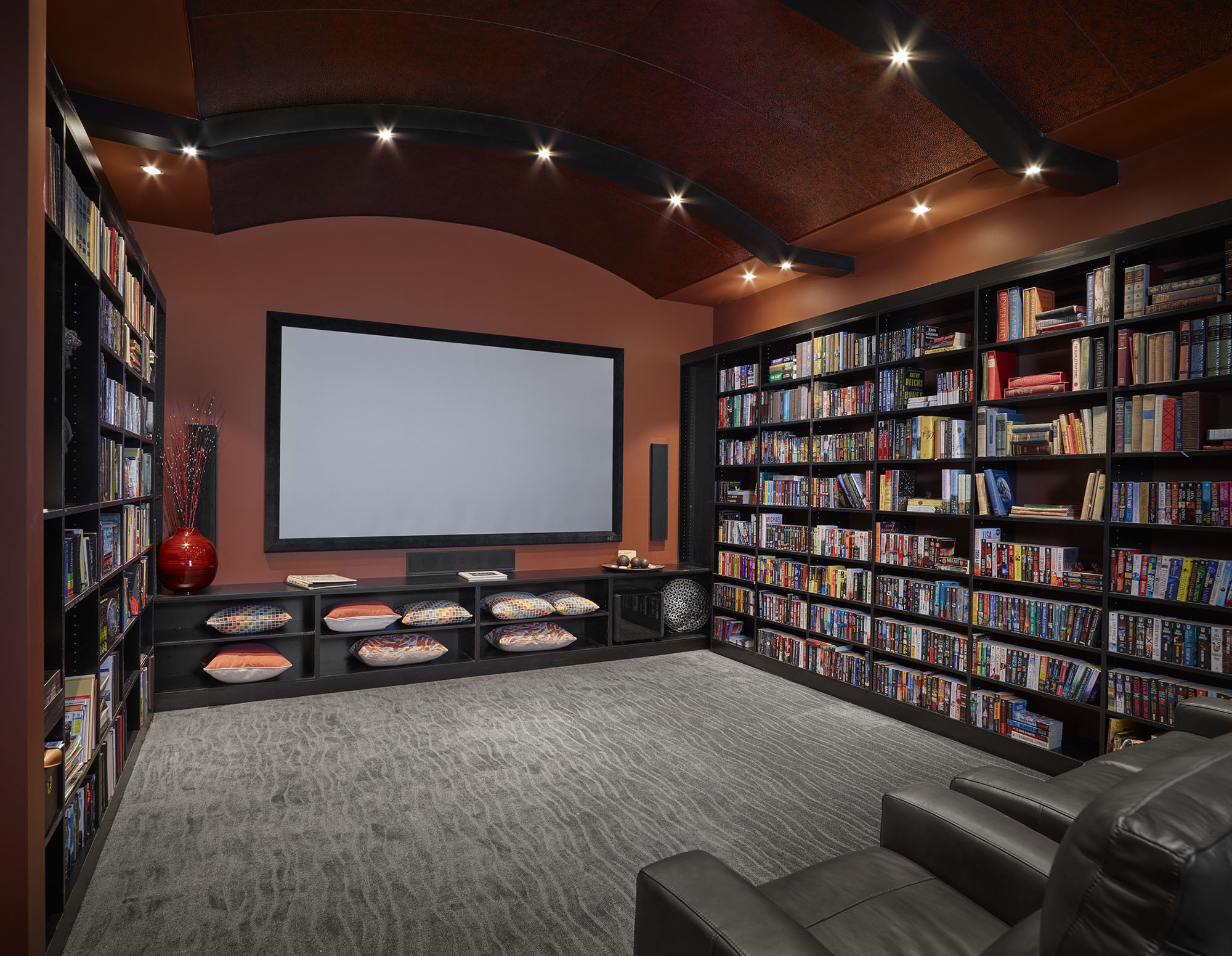 custom entertainment room with built in shelving large movie screen and recliners