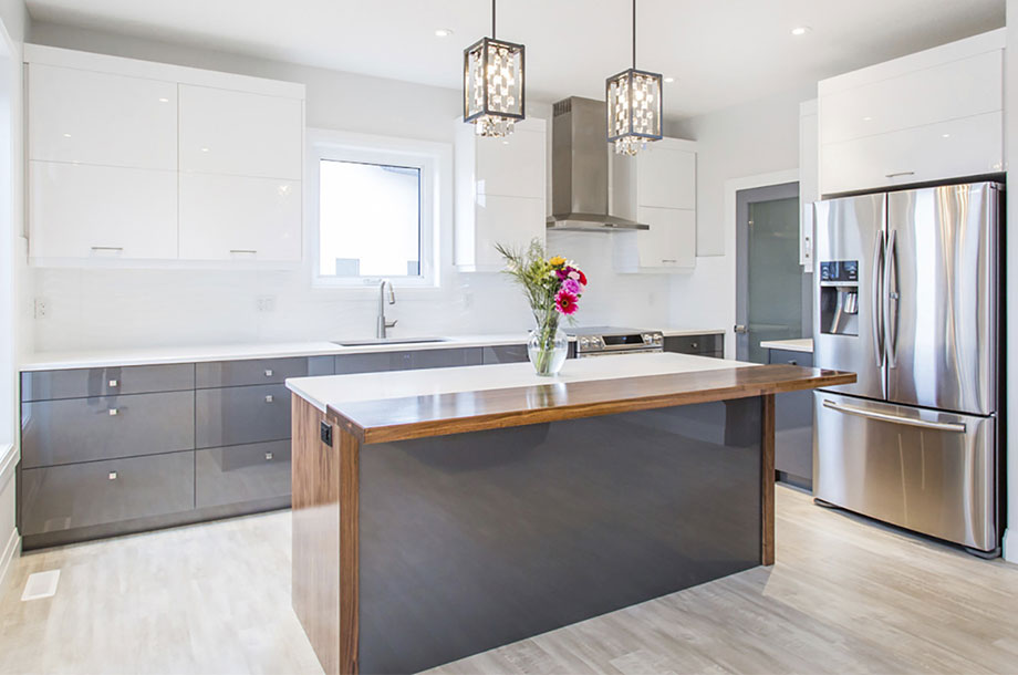 clean modern kitchen with glossy grey island and white counter tops and vase of roses at center