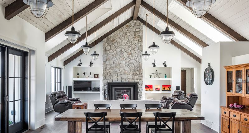 Dining room with light walls and stone fireplace with exposed beams