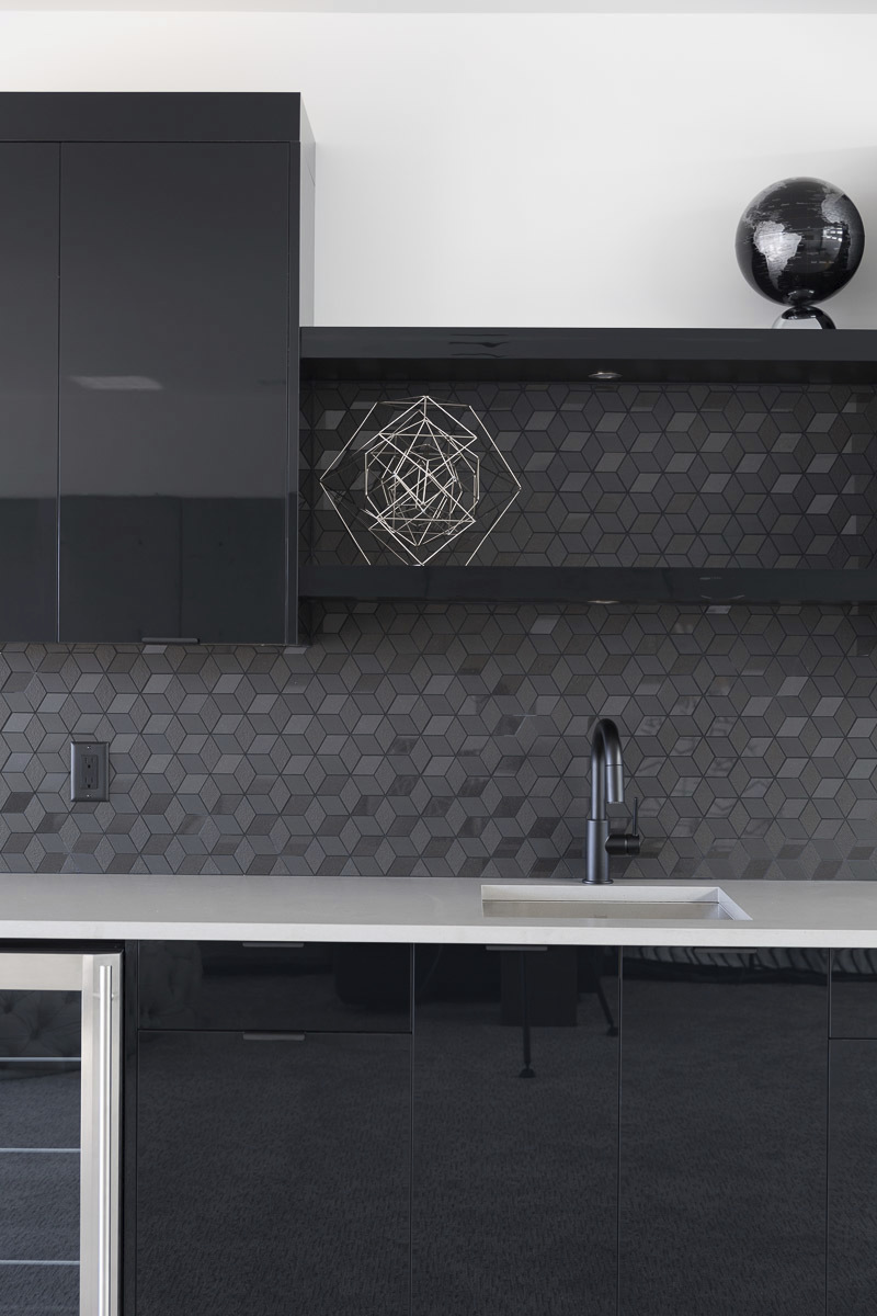 modern kitchen all sleek black appliances with white counters and black geometric patterned backsplash