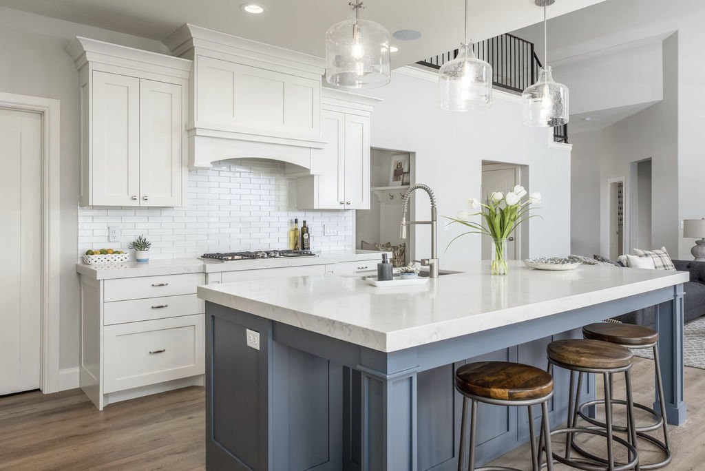 Custom built kitchen with all white cabinets, geometric backsplash and a grey-blue painted island
