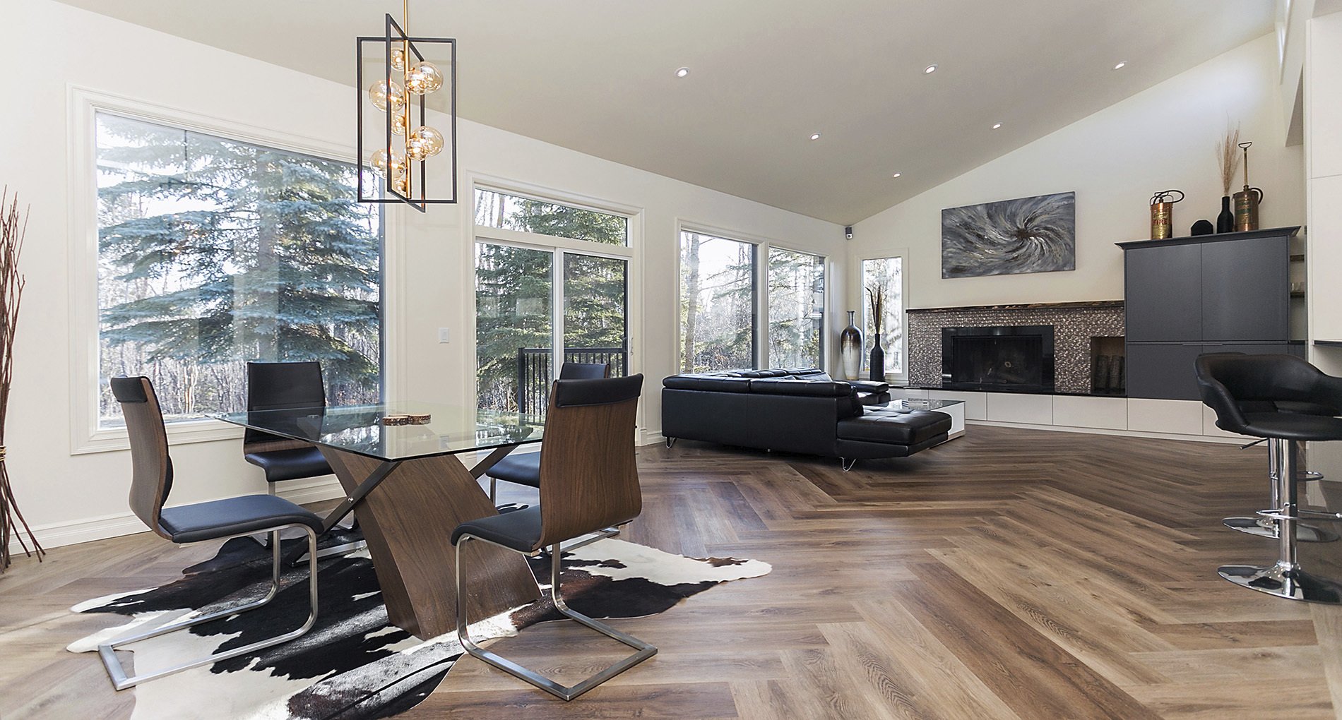 Modern custom living space with patterned wood flooring, a fireplace and big windows.