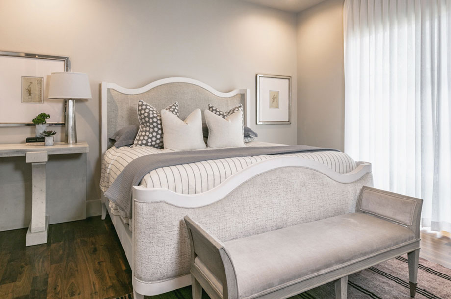 grey and white guest suite with small seat at the edge of bed and access to small patio