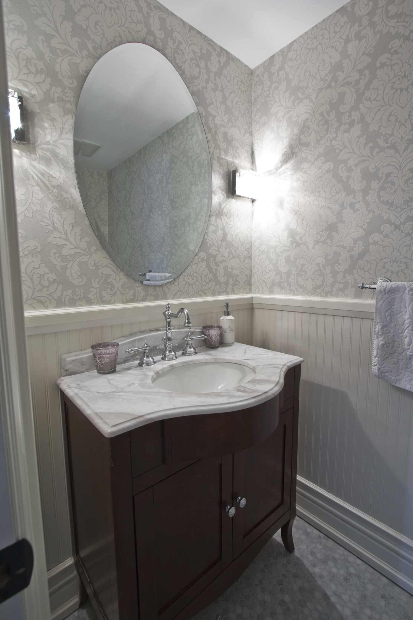 half bath with marble grey wallpaper and dark stained wood cabinet below marble sink 