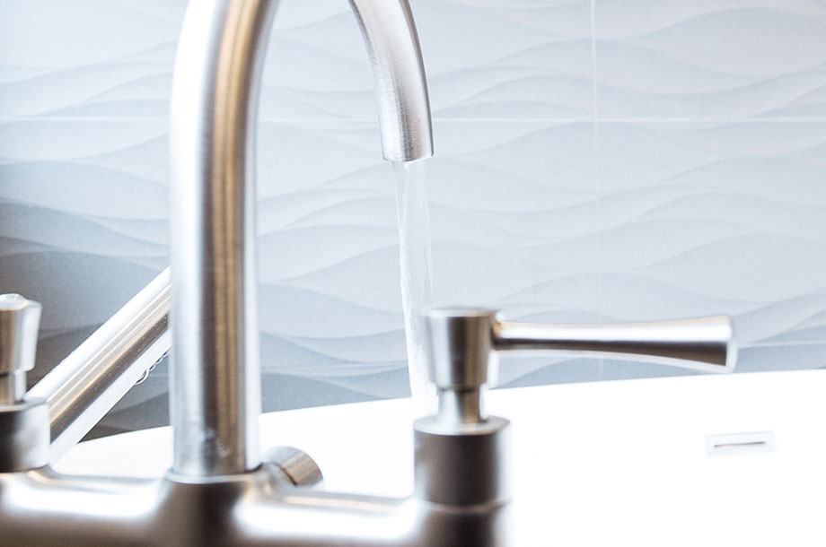 close up of stainless steel faucet pouring water