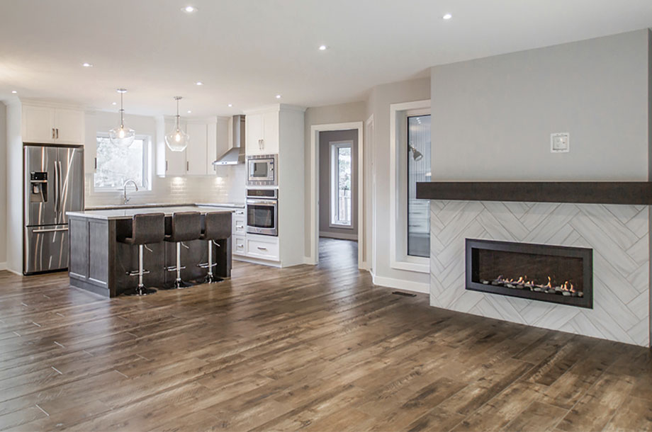 empty living area with modern fireplace and kitchen in background