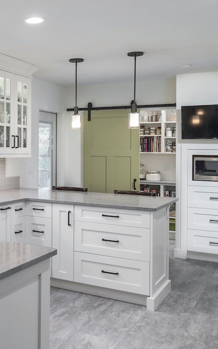 Custom kitchen with all white cabinetry and sliding jade green door to pantry.