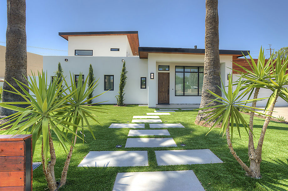 exterior of beautiful cream colored adobe style custom home with lush turfgrass lawn
