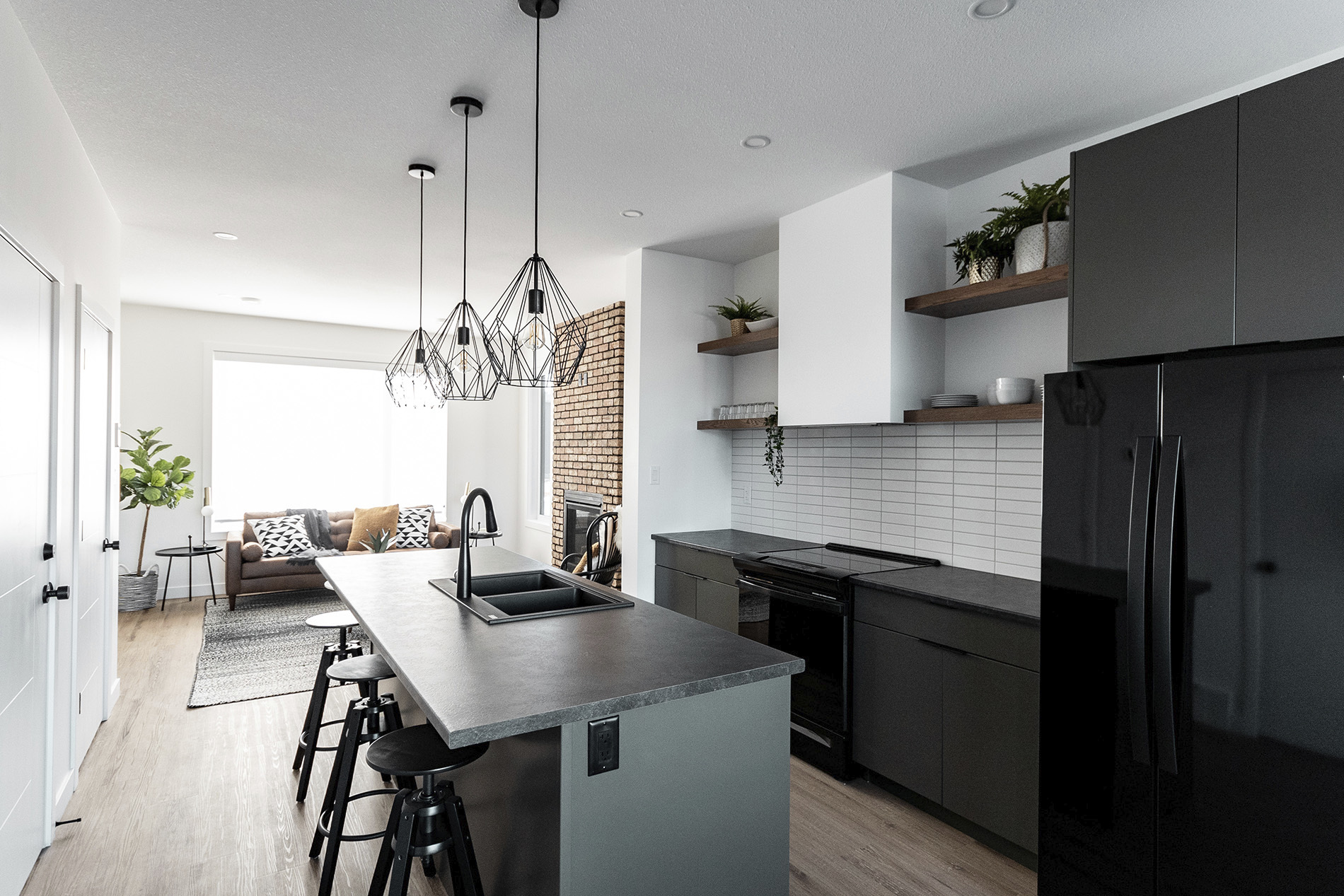 custom kitchen with black finishes white walls with minimalist shelving and custom light fixtures over island