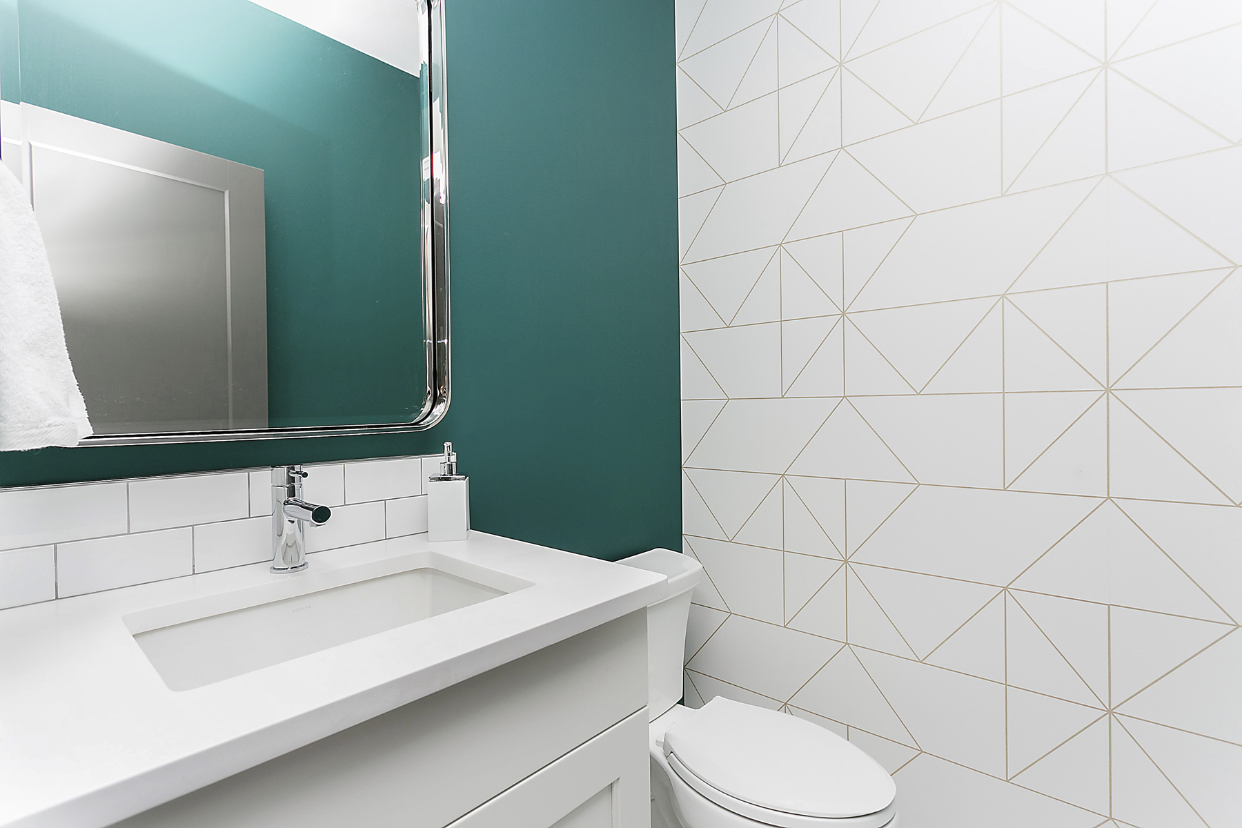 bathroom with sink against teal wall and geometric gold pattern on white wallpaper on feature wall