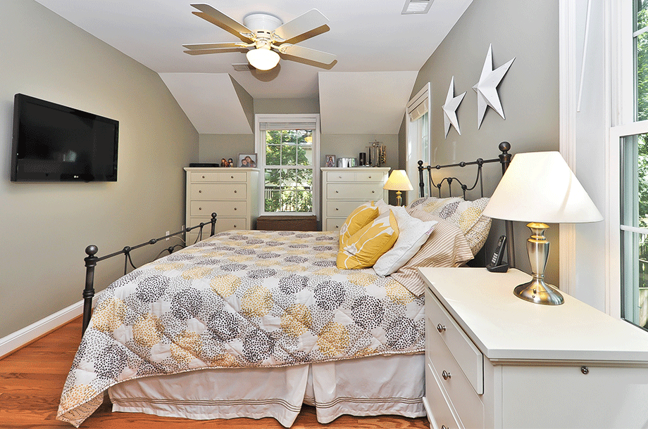 guest room with mounted tv and yellow and grey bedding