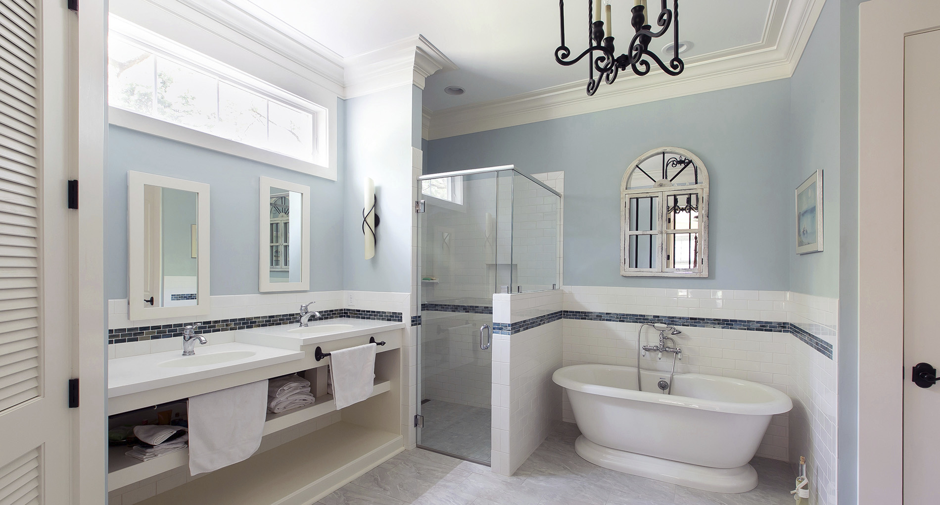 Light blue bathroom with destination tub and custom heights for each sink with cabinet space below for towels. 