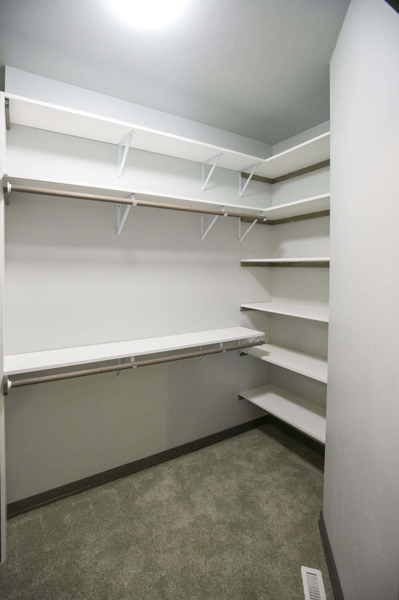 empty all white closet with built in shelving and additional lower rods
