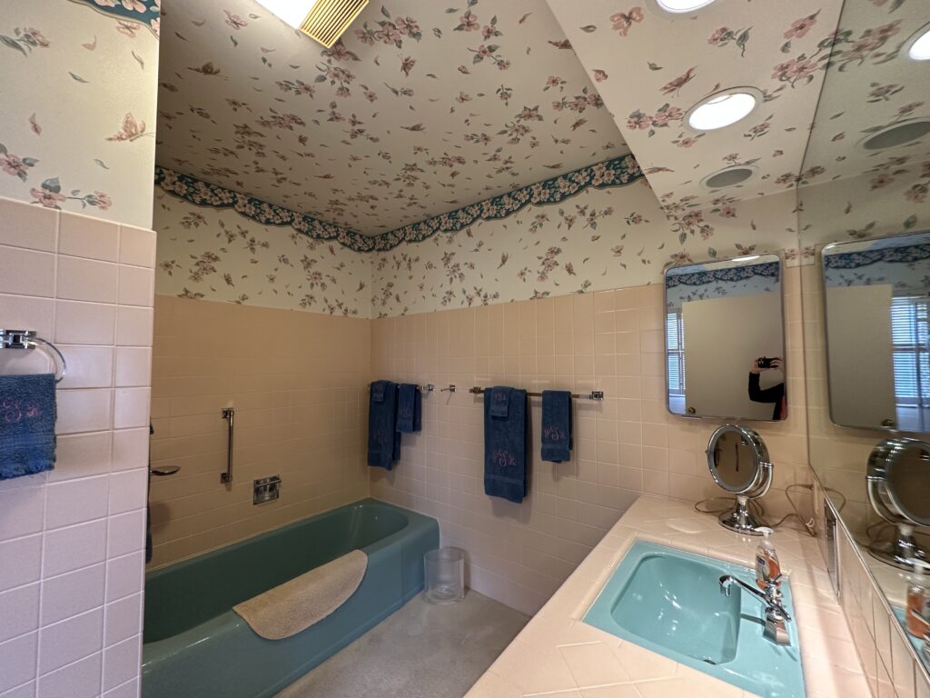 Outdated bathroom with floral wallpaper and mint fixtures