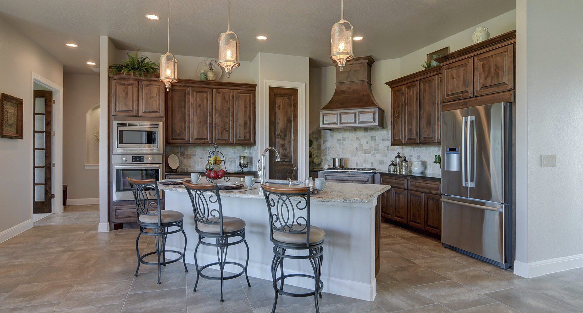 custom kitchen with wood cabinets iron finishing and patterned cream stone backsplash