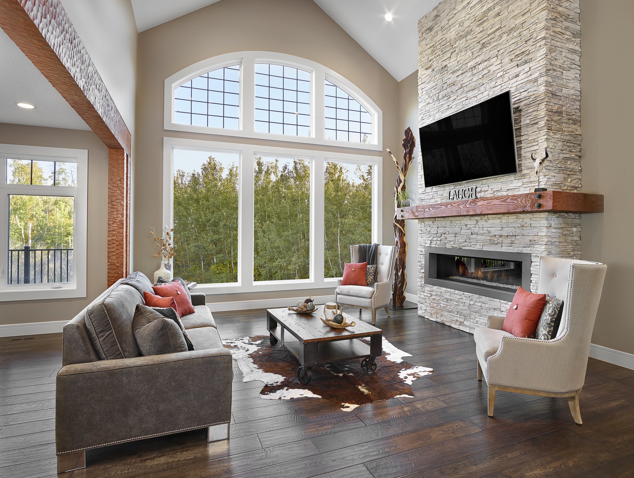 Living area with high ceilings large cream stone fireplace red pillows on neutral colored sofas