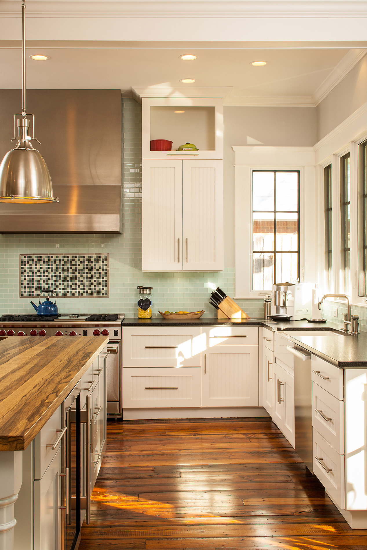 Custom kitchen with stainless steel appliances, warm wood top island and geometric backsplash