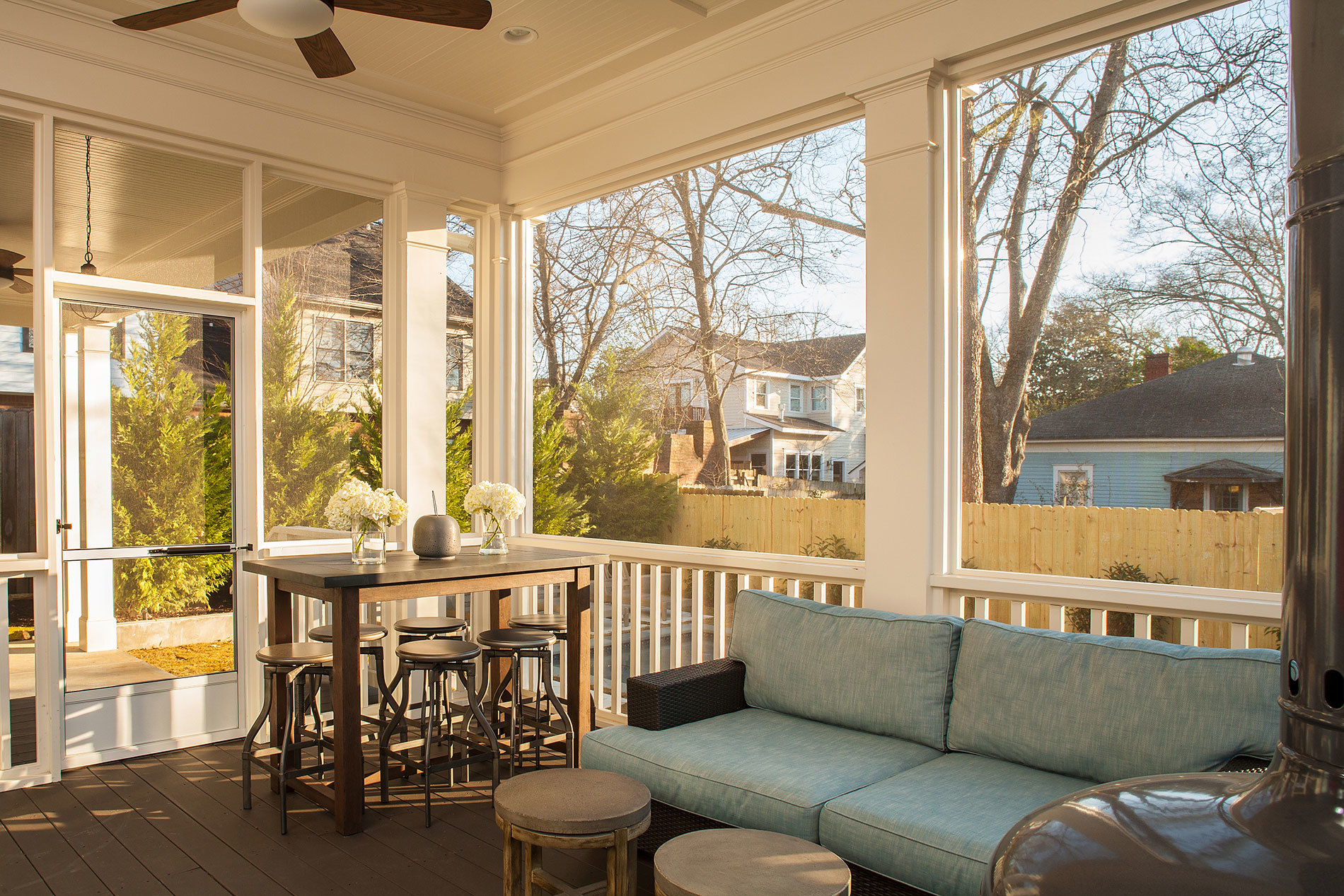 enclosed sun room with blue cushioned couch and small elevated table