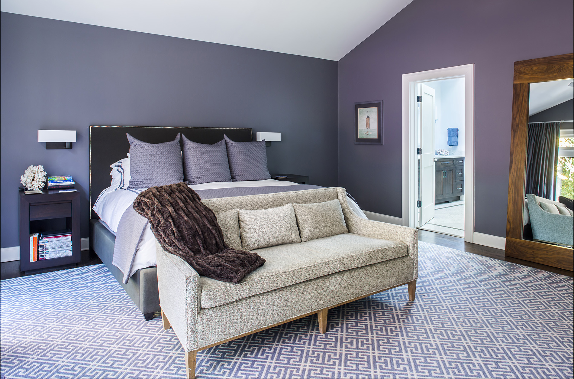 cozy guest bedroom with extra blankets and small couch at the foot of the bed